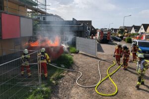Brennende Mulde auf Baustelle, Feuerwehr im Einsatz während eines angekündigten Unwetters.
