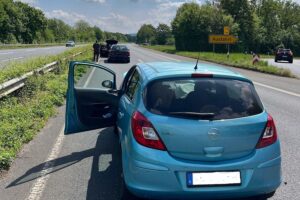Ein Unfallort mit Einsatzfahrzeugen, beschädigten Autos und einer verletzten Fahrerin auf der Straße.