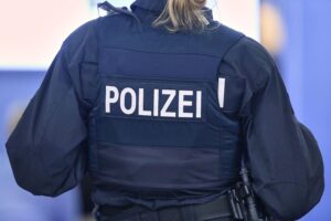 Polizisten stehen vor einem Mehrfamilienhaus, SEK-Einsatz nach Bedrohung mit Schusswaffe.