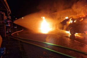 Feuerwehr löscht Gebäudebrand in Gundelfingen, Flammen und Rauch steigen aus Werkstattkomplex auf.