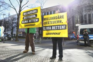 Greenpeace-Protest mit Aktivisten, Transparenten und Forderungen gegen Vermögenskonzentration und Klimakrise.