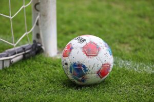 Fußballspiel mit Spielern in Vereinsfarben, symbolisiert Wechsel und Veränderungen im Team.