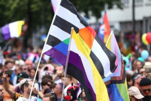 Fahnen, Menschen und Feierlichkeiten zur Unterstützung von Vielfalt und LGBTQ+ Rechten während einer Parade.