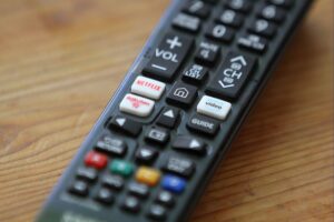 TV-Fernbedienung vor verschiedenen Streaming-Anbieter-Logos, symbolisiert Investitionsverpflichtungen in Deutschland.