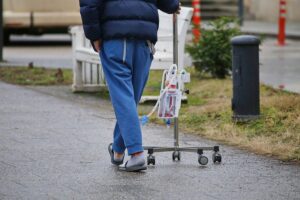 Ein kranker Patient mit Infusionsständer im Krankenhaus, Symbol für finanzielle Belastung der Pflege.