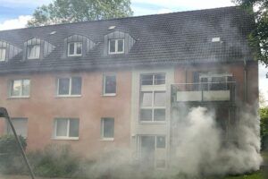 Einsatzkräfte löschen Kellerbrand; Bewohner evakuiert; Rauch dringt aus dem Gebäude. Feuerwehr im Einsatz.