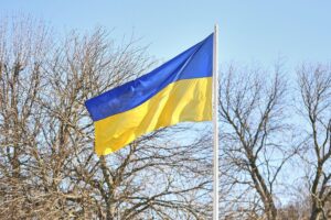Ukrainische Fahne mit europäischem Hintergrund, um den Ruf nach diplomatischer Zusammenarbeit zu verdeutlichen.