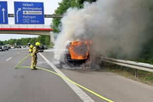 Brand eines PKW auf der Autobahn, Feuerwehr im Einsatz, Fahrzeug in Flammen.