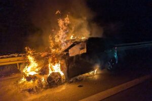 Flammen umgeben ein brennendes Auto auf der Autobahn, Feuerwehr im Einsatz, Familie gerettet.