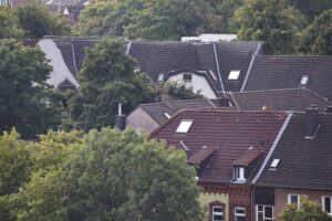Dächer von Wohnhäusern, symbolisieren notwendige Sanierungen und rechtliche Reformen in Gemeinschaften.