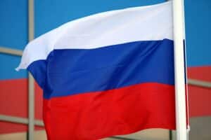 Russische Fahne vor dramatischem Hintergrund; symbolisiert die aggressiven militärischen Aktionen gegen die Ukraine.