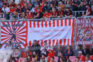 Fans des SC Freiburg jubeln, während Torhüter Jannik Huth für seinen Vertrag posiert.