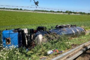 Umgestürzter Sattelzug auf Radweg, Feuerwehr im Einsatz, Polizei und Rettungsdienst an Unfallstelle.