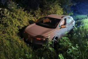 Unfallstelle mit einem beschädigten Roller und Polizei vor einem Verkehrsschild bei Nacht.