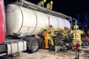 Schwerer Verkehrsunfall mit beschädigtem Audi und Sattelzug; Rettungskräfte arbeiten am Unfallort.