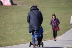 Familie spielt gemeinsam im Freien; Vater, Mutter und Kind interagieren fröhlich und entspannt.