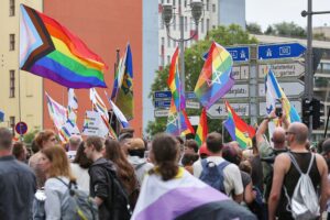 Bunte Parade mit festlichen Teilnehmern, Wimpeln und Symbolen der LGBTQ+-Gemeinschaft in New York.