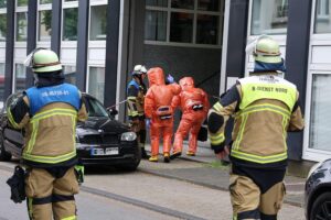 Einsatzkräfte in Chemikalienschutzanzügen untersuchen potenziellen Gefahrstoff in einem Bürogebäude.