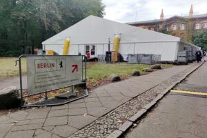 Flüchtlingsankunftszentrum mit Beratern, symbolisiert Rückkehrprämien und Debatte zur Rückkehrhilfe.