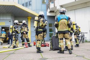 Laborbrand mit Rauchentwicklung: Feuerwehr und Rettungsdienst im Einsatz, verletzte Person wird versorgt.