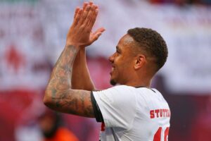 Nikolas Nartey feiert Vertragsverlängerung beim VfB Stuttgart bis 2028, jubelnde Fans im Hintergrund.