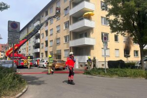 Rettungskräfte bekämpfen Wohnungsbrand, verkohlte Wohnung, Feuerwehr im Einsatz, stark verrauchter Treppenraum.