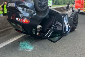 Ein überschlagener Pkw auf der Autobahn, umgeben von Polizei und Bergungsfahrzeugen.