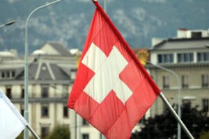 Fahne der Schweiz, Symbol für wirtschaftliche Stärke und Offenheit, vor Herausforderungen durch Immigration.