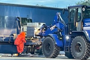 Einsatzkräfte bergen einen IBC-Container auf Rastplatz, während Gefahrstoffe ausgeflossen sind.