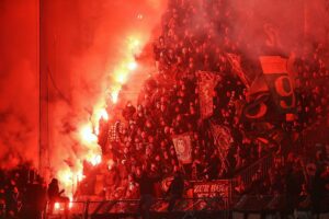 Fans zünden Bengalos im Stadion, während Diskussionen über Pyrotechnik und Sicherheitsmaßnahmen stattfinden.