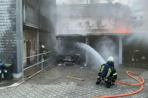 Feuerwehr im Einsatz: Löscharbeiten an einem brennenden Auto unter Carport in Mülheim.