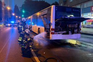Brennender Bus an Haltestelle, Feuerwehr im Einsatz, Passanten helfen, keine Verletzten.