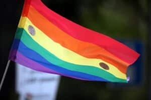 Regenbogenfahne schwingt über buntem CSD-Zug in Pforzheim, friedliche Feier der Vielfalt und Akzeptanz.