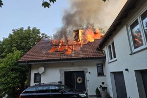 Dachstuhlbrand mit Feuerwehr im Einsatz, Löschaktionen und Drehleiter sichtbar.