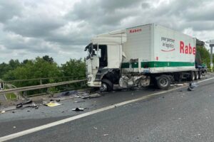 Zwei verunfallte Lastwagen auf der Autobahn, Feuerwehr im Einsatz, Verletzte werden behandelt.