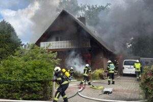 Einsatzkräfte der Feuerwehr kämpfen gegen Wohnhausbrand, Menschenrettung und Brandbekämpfung im Fokus.