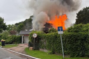 Ein brennendes Einfamilienhaus mit intensiven Löscharbeiten der Feuerwehr im Vordergrund.