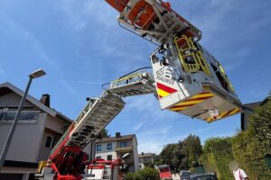 Retter mit Drehleiter transportieren verletzte Person vom Balkon zu Rettungswagen in Sprockhövel.
