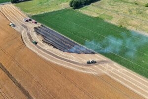 Flächenbrand auf Feld, Feuerwehr im Einsatz, Traktoren, Mähdrescher, Drohne überwacht Brandbekämpfung.