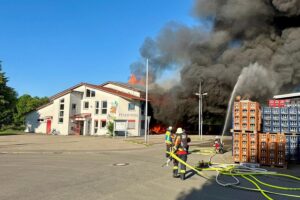 Großbrand im Feuerwehrhaus Unterensingen, Einsatzkräfte löschen Flammen und sichern die Umgebung.