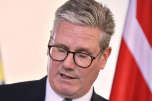 Keir Starmer kündigt Rücktritt an, farbenfroher Hintergrund mit Labour-Logos und britischer Flagge.