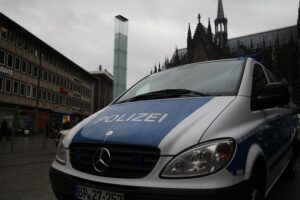 Polizeiauto vor Kölner Dom symbolisiert Sicherheitsdebatte um Mikrohandel mit Drogen in Städten.