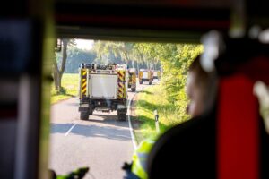 Vielzahl von Einsatzkräften bei Feuerwehrübung mit Zelten und Fahrzeugen unter erschwerten Bedingungen.