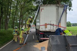 Lkw mit beschädigtem Auflieger, Spanngurte sichern Ladung auf Fahrbahn, Feuerwehr im Einsatz.