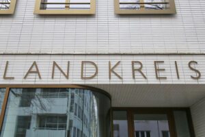 Schriftzug des Landkreises überlagert von besorgten Kommunalvertretern und finanziellen Grafiken.