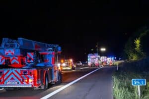 Unfallstelle auf der Autobahn mit beschädigtem Fahrzeug, Feuerwehr und Rettungsdiensten im Einsatz.