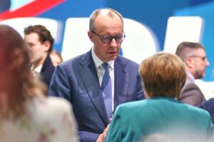 Angela Merkel und Friedrich Merz im Gespräch über politische Entwicklungen und Erwartungen der Regierung.