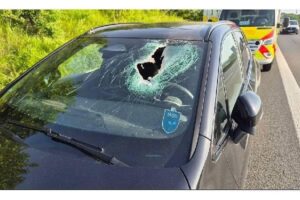 Durchschlagene Windschutzscheibe eines BMW nach Unfall auf Autobahn, Metallteil verletzte Fahrer.