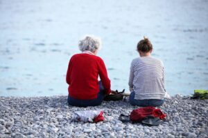Alte und junge Frauen am Strand symbolisieren den generationsübergreifenden Dialog über Rentenfragen und Zukunft.