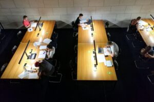 Studenten in einer Bibliothek, die für Bafög-Reform und finanzielle Unterstützung lernen und diskutieren.